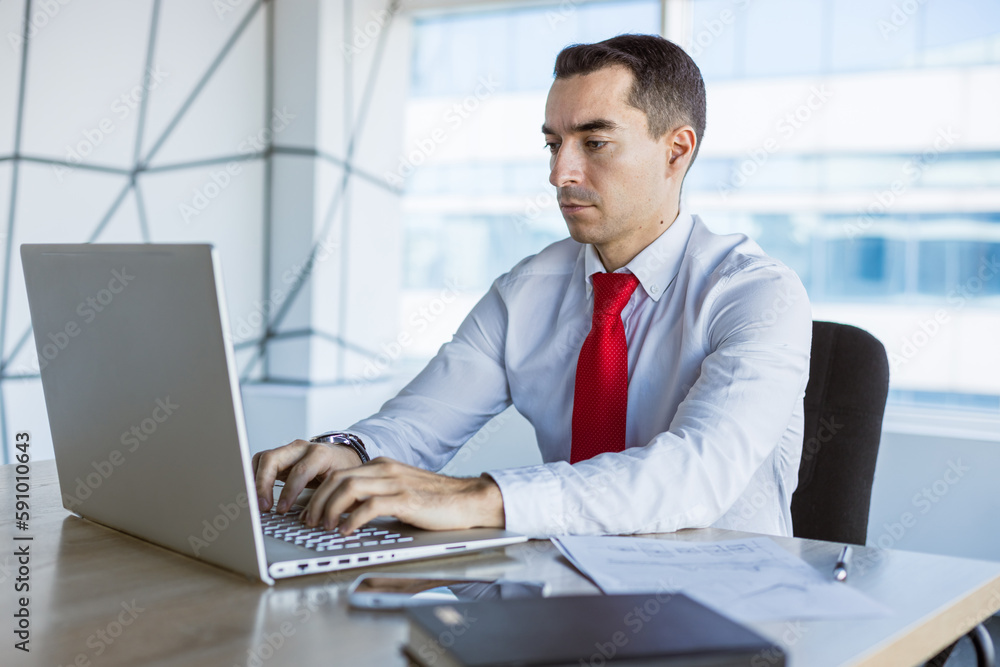 Portrait of a business young successful man in a modern office sitting at a table Portrait of a business young successful man in a modern office sitting at a table