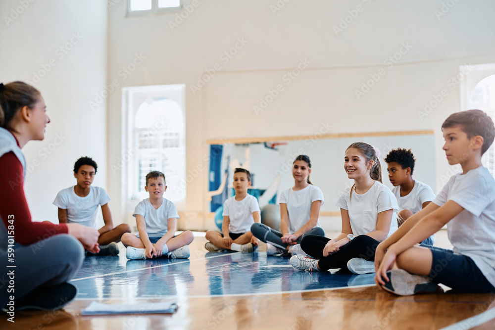 Group of kids talk to their sport teacher on PE class at school gym. Group of kids talk to their sport teacher on PE class at school gym.