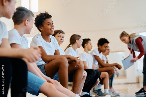 Happy black boy and his classmates during PE class at school gym.