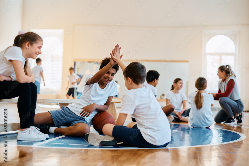 Happy boys giving high five on PE class at school gym. Happy boys giving high five on PE class at school gym.