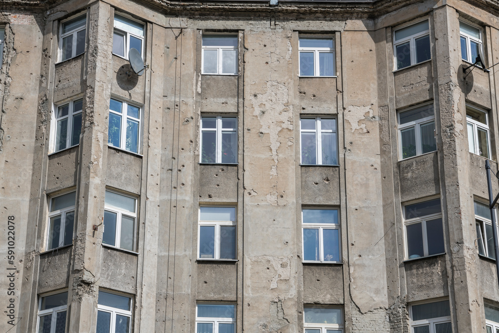 Obraz premium Old gray apartment block wearing the sign of world war II in Warschau. Damaged, old, soviet style, ugly