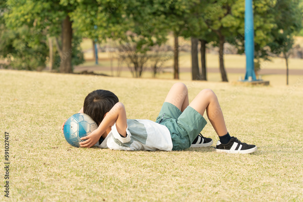 Fototapeta premium 芝生で寝そべる小学生の男の子
