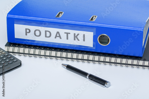 Niebieski segregator z fakturami firmowymi leżący na kołonotatniku na biurku w pracy