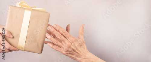 Hands of an elderly woman receiving a gift from a girl. Close-up.