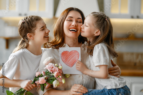 Daughters giving mother bouquet of flowers.