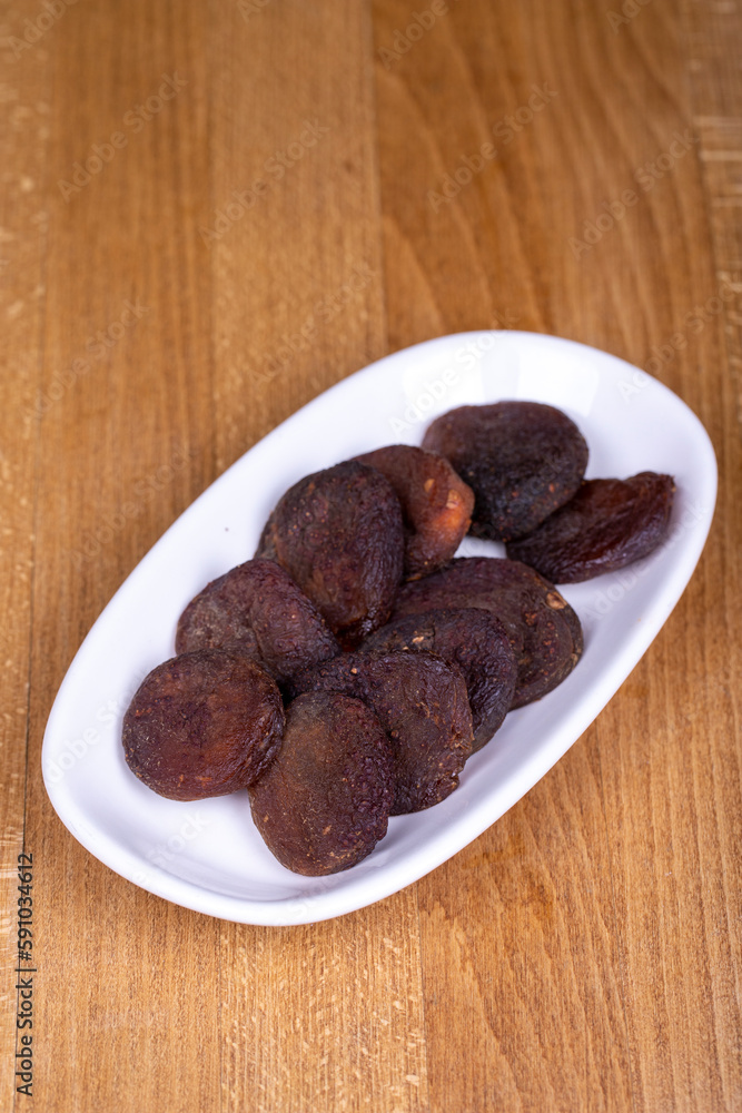 Dried apricots. Organic sun-dried apricots on wood background. Naturally Dried apricots color orange in a ceramic bowl. Close up Dried apricots. Organic sun-dried apricots on wood background. Naturally Dried apricots color orange in a ceramic bowl. Close up
