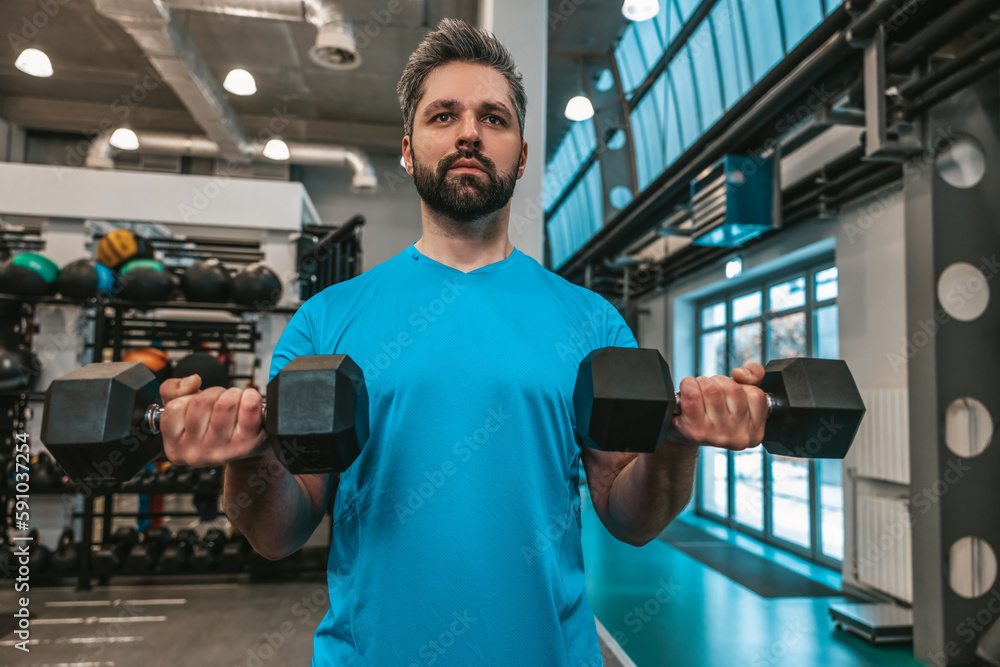 Young athlete working on his muscles with dumbbells Young athlete working on his muscles with dumbbells