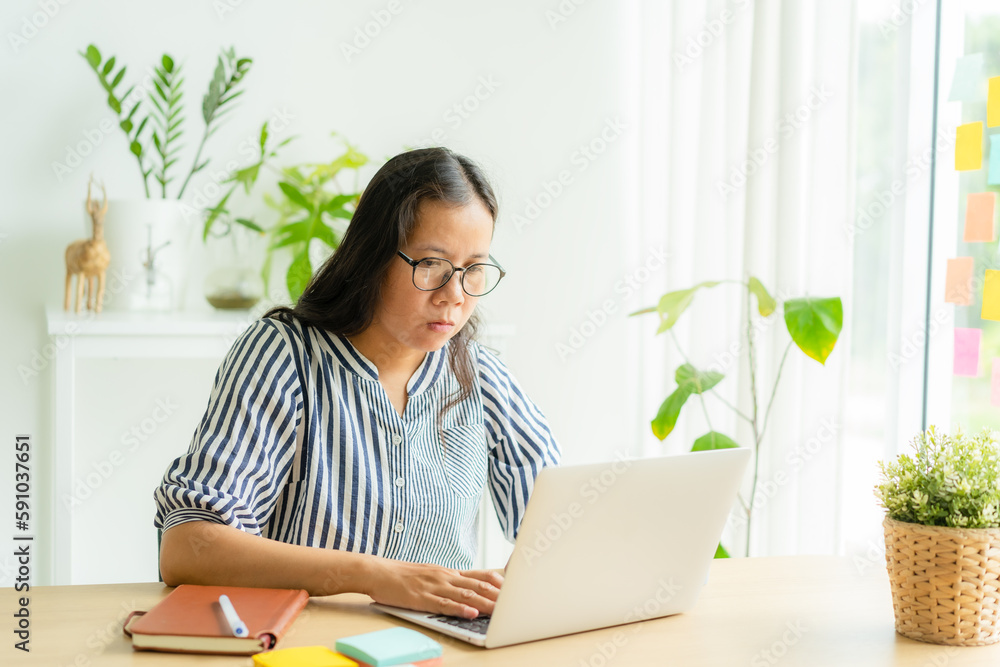 Asian woman using laptop, typing, working at home morning Asian woman using laptop, typing, working at home morning