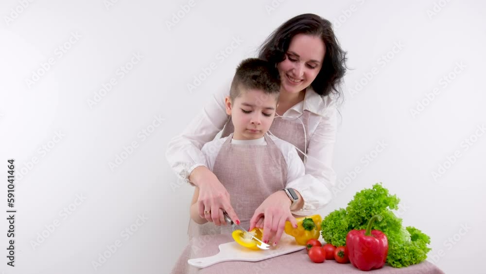 Attentive mother helping her son to cut vegetables in kitchen Attentive mother helping her son to cut vegetables in kitchen