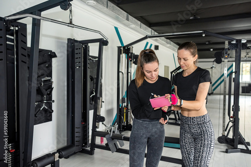 personal trainer and trainer woman helps a beauty in the gym. © RomanR