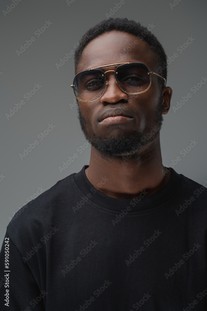 Φωτογραφία Shot of trendy black guy dressed in t shirt and sunglasses looking at camera
