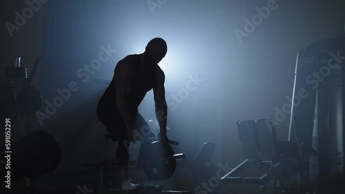 Silhouette of an athlete working on his muscles with weights. Work on your appearance in the gym. High quality 4k footage