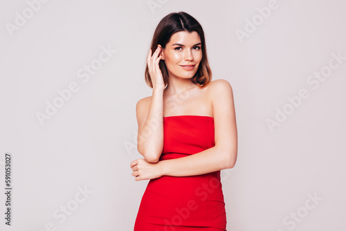 Young beautiful smiling female in trendy summer red evening dress. Sexy carefree brunette woman posing in studio, isolated on white. Positive model with evening makeup. Cheerful and happy