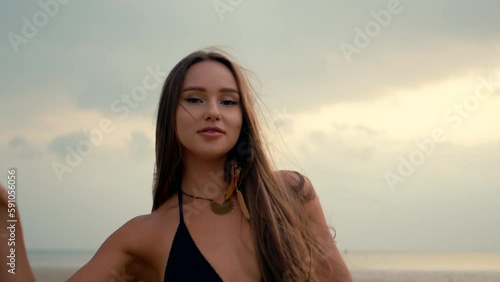 beautiful girl with long straight hair dancing on the beach, watching the sunset
