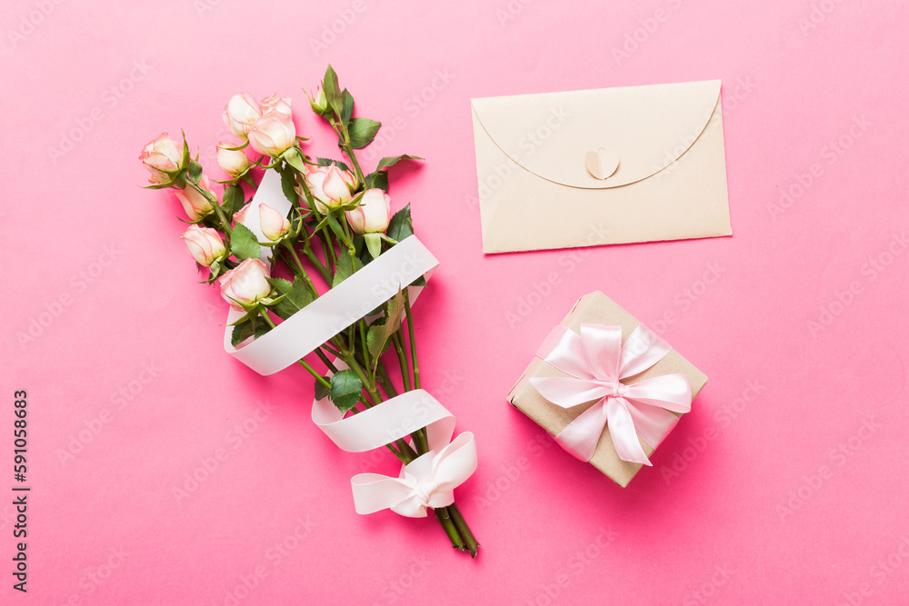 Greeting card mockup with copy space, pink ribbon and roses flowers on colored table background. Flat lay, top view. mother day holiday concept Greeting card mockup with copy space, pink ribbon and roses flowers on colored table background. Flat lay, top view. mother day holiday concept
