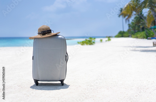 A suitcase and a straw hat against the backdrop of the landscape of the Maldives. Travel and tropical vacation concept © Marina