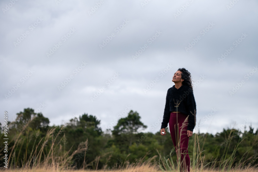 Woman standing in field with vaporizer in hand