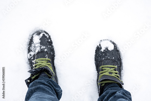 Men's feet in boots in deep snow, top view.
