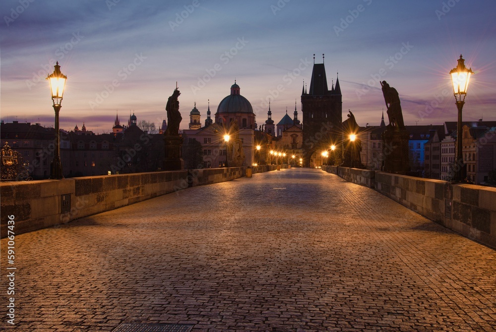 Scenic view of the Charles Bridge surrounded by traditional buildings in evening in Prague