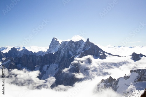 Aerial view of snowcap Grandes Jorasses mountain peak above the white clouds photo