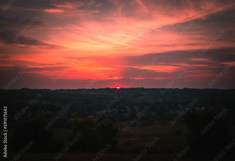 Bright sunset shining over the small town in the red and pink sky behind the horizon