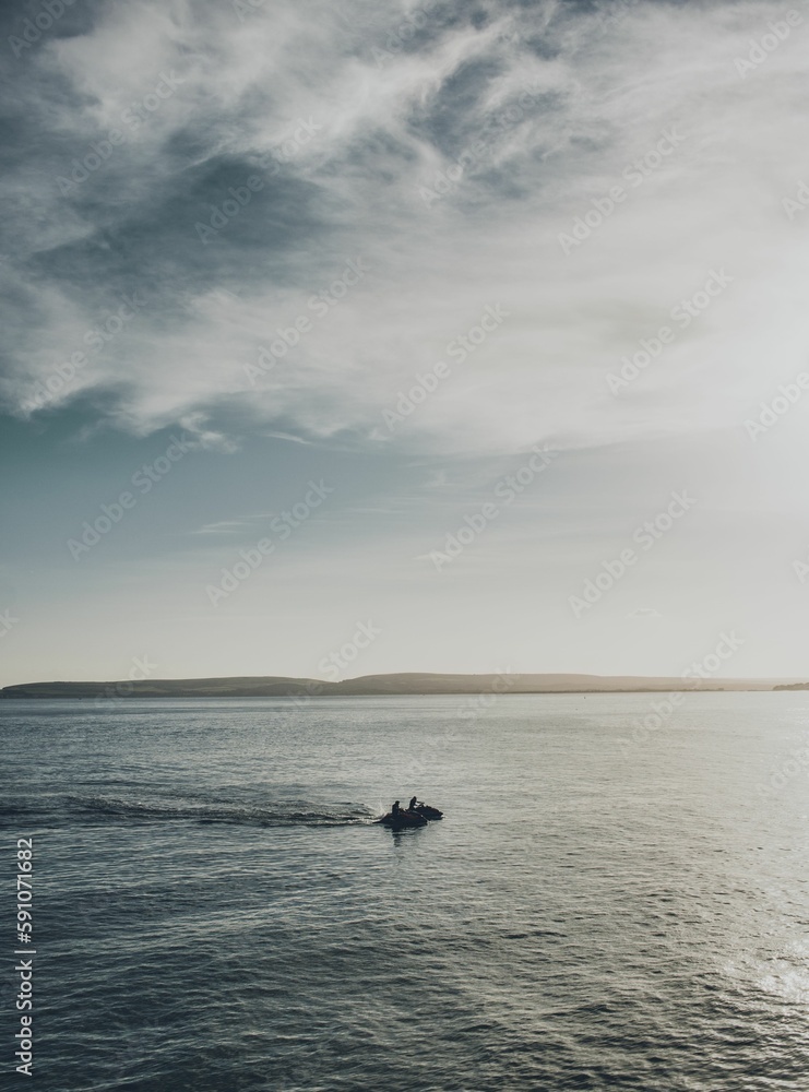 Vertical of people riding a water scooter in the sea on a beautiful day Vertical of people riding a water scooter in the sea on a beautiful day