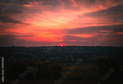 Fototapeta Naklejka Na Ścianę i Meble -  Bright sunset shining over the small town in the red and pink sky behind the horizon