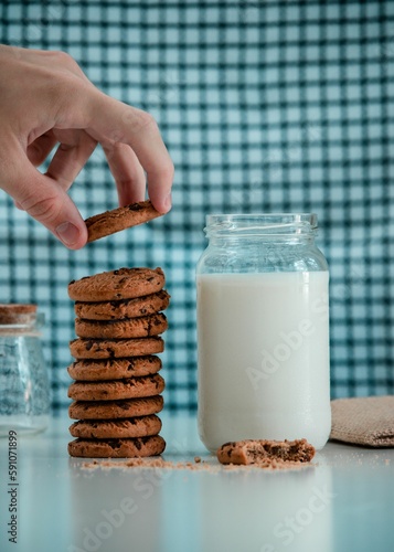 Closeup of tasty cookies with a jar of milk on the table on blue background