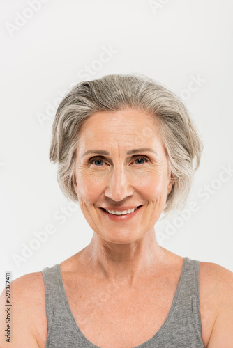 portrait of overjoyed senior woman smiling and looking at camera isolated on grey.