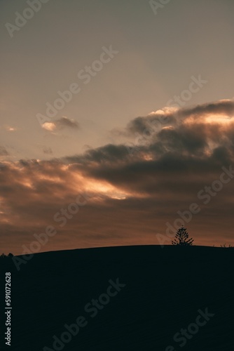View of the sunset in an orange sky from the dark hill. © George Fallon/Wirestock Creators