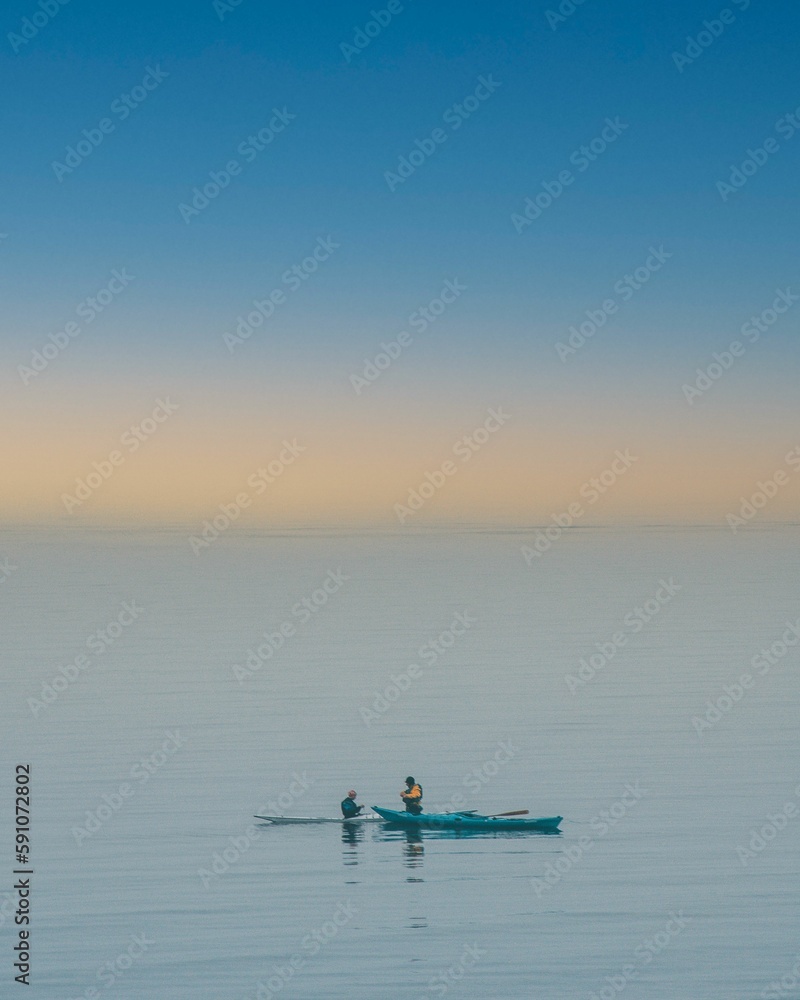 Naklejka premium View of two boats in the blue sea under the yellow sky.
