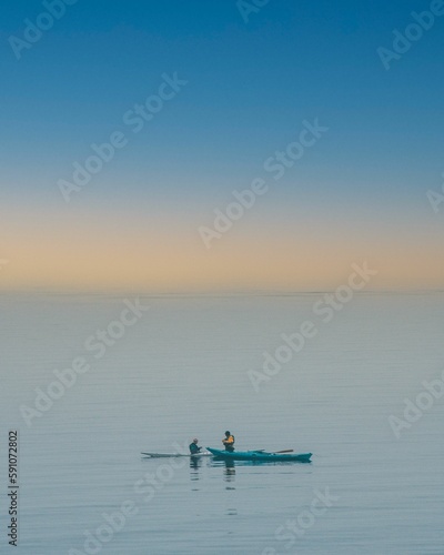 View of two boats in the blue sea under the yellow sky.