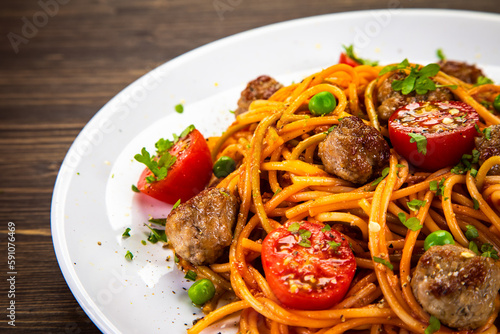 Spaghetti with meatballs in tomato sauce on wooden table
