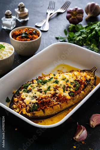 Roasted aubergine stuffed with minced meat and cheese on wooden table
