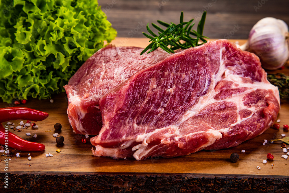 Fresh raw slices of pork neck on cutting board on wooden table
Fresh raw slices of pork neck on cutting board on wooden table