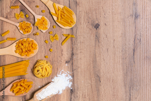 Vari mix di pasta su fondo rustico in legno, sacco e cucchiai di legno. Concetto di dieta e cibo.
