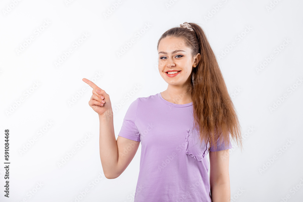 Enthusiastic young woman with long hair, pointing finger left and look happy, showing great promo offer aside, standing in casual t shirt over white background Enthusiastic young woman with long hair, pointing finger left and look happy, showing great promo offer aside, standing in casual t shirt over white background