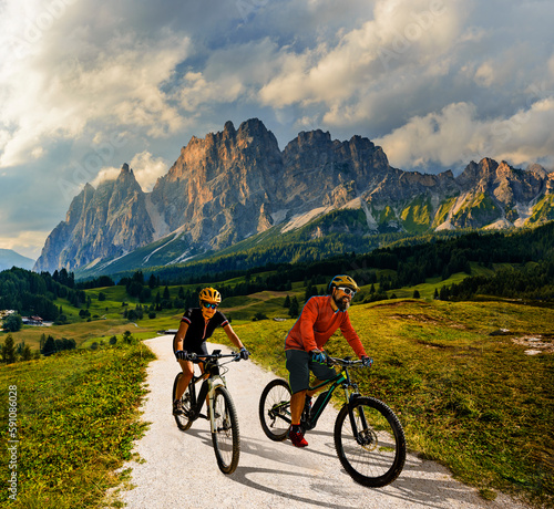 A man and woman ride electric mountain bikes in the Dolomites in Italy. Mountain biking adventure on beautiful mountain trails.