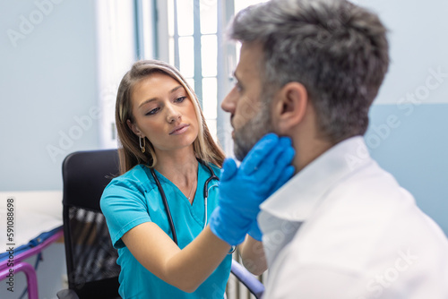 Endocrinologist examining throat of man in clinic. Men with thyroid gland test . Endocrinology, hormones and treatment. Inflammation of the sore throat