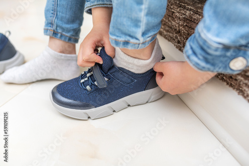 Children's hands on sneakers when putting on shoes. Close-up.