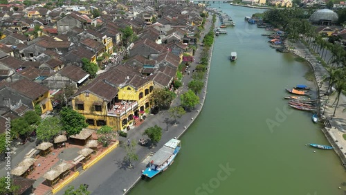 Beautiful drone footage in Hoi An ancient town along the riverside in central Vietnam. Camera is moving foward above the river and the roofs of the old city. 1-3 photo