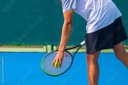 Tennis player playing tennis on a hard court on a bright sunny day 