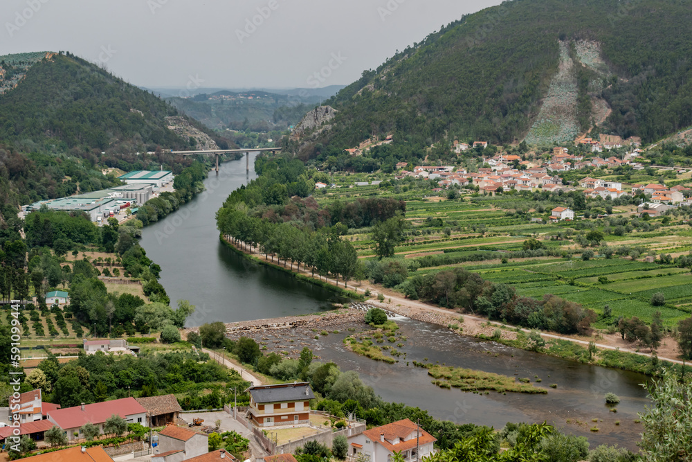 Houses and agricultural fields in aerial view with Mondego river and stone weir in the center and mountains in the horizon, Penacova PORTUGAL