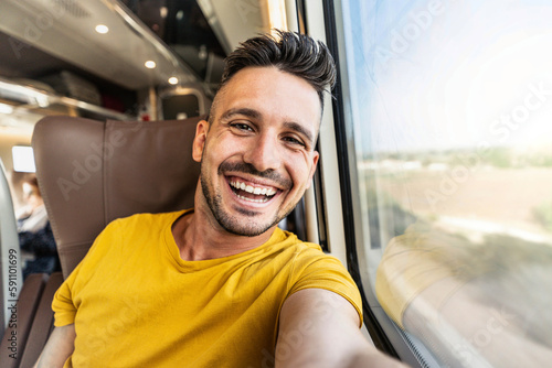 Happy male tourist taking selfie sitting in the train - Transportation, tourism and travel concept photo