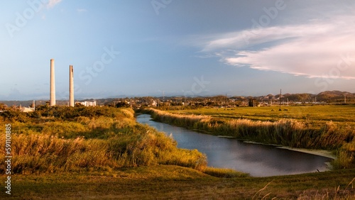 Scenic view of a narrow river flowing amid the fields under the blue sky