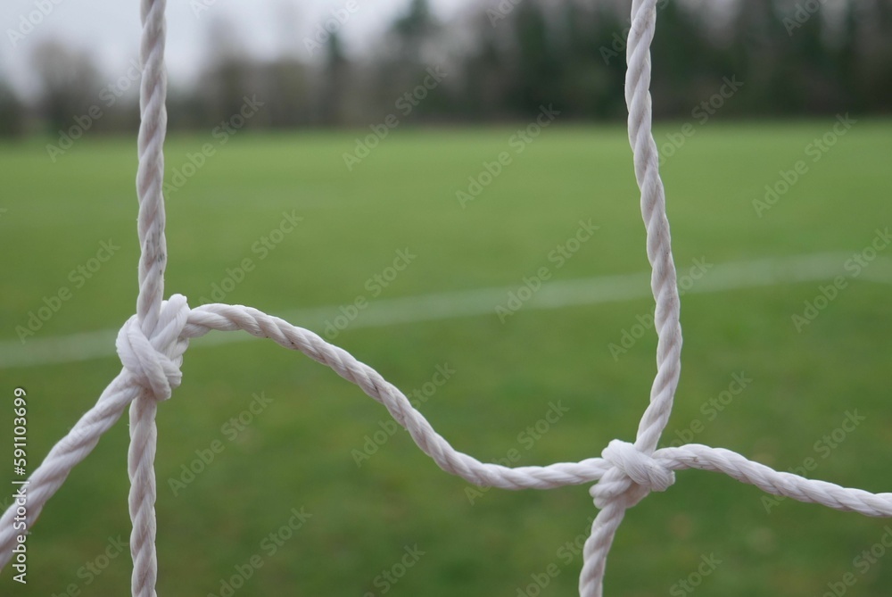 Closeup shot of goal ropes for playing football with green lawn in the background Closeup shot of goal ropes for playing football with green lawn in the background