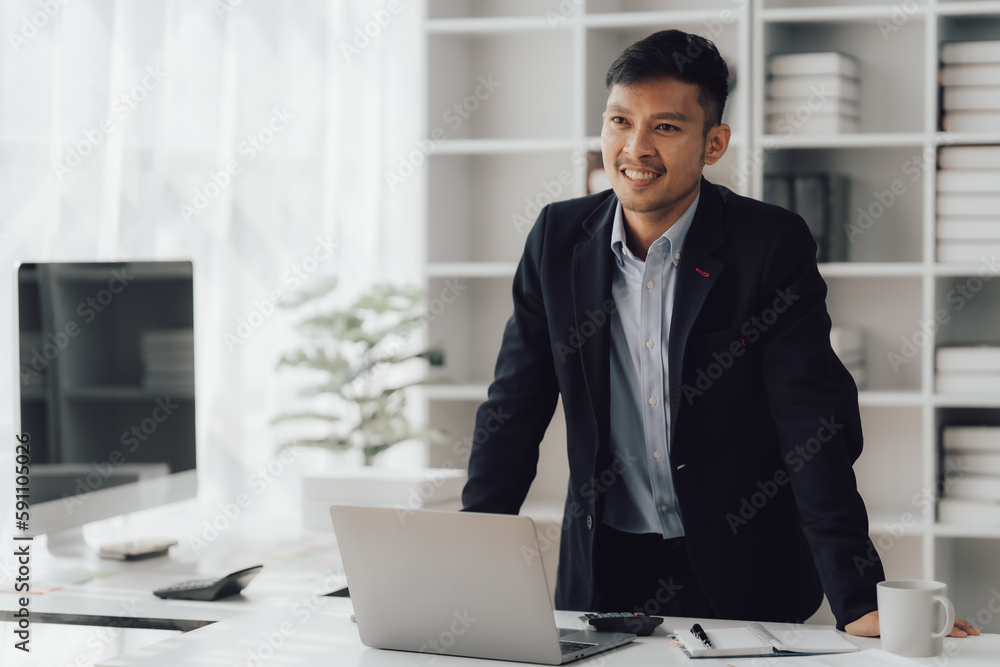 Happy working asian businessman talking on the phone with accounting documents at desk in happy working office Happy working asian businessman talking on the phone with accounting documents at desk in happy working office