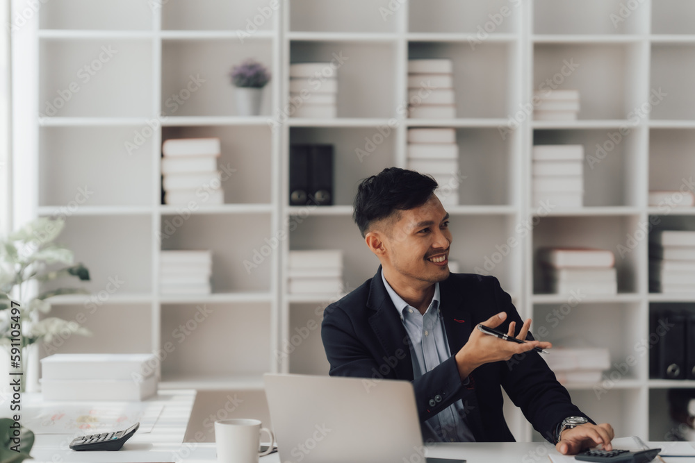 Happy working asian businessman talking on the phone with accounting documents at desk in happy working office Happy working asian businessman talking on the phone with accounting documents at desk in happy working office