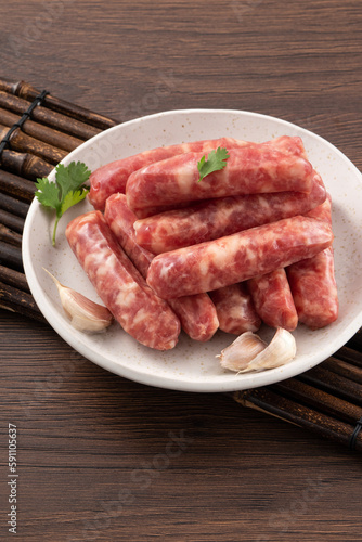 Raw Taiwanese sausage in garlic flavor in a plate on wooden table background.