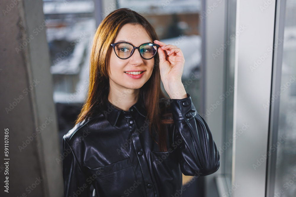 Fototapeta premium Portrait of a smiling woman in glasses for vision correction. Young business woman near the window